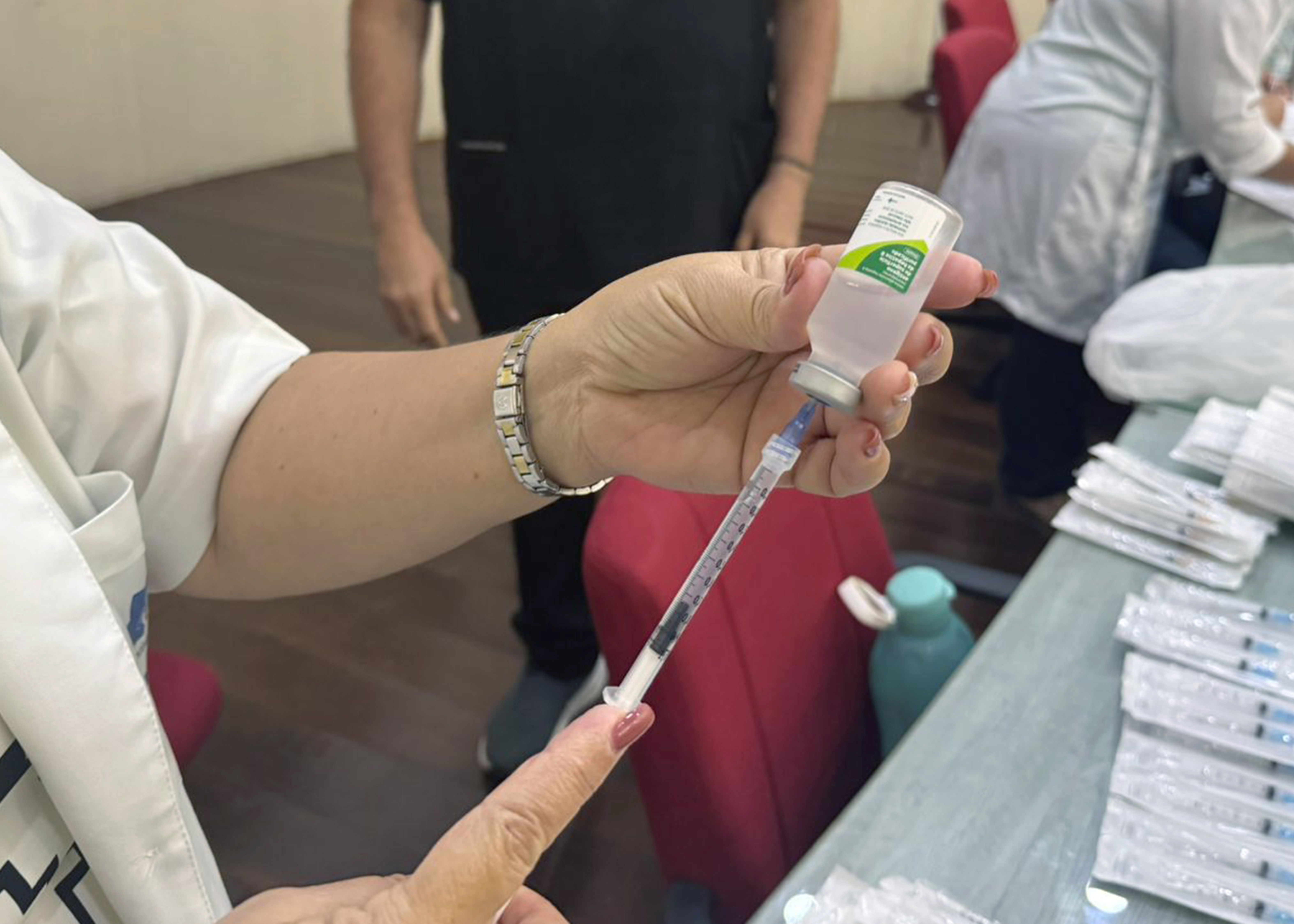 Na imagem aparece uma enfermeira preparando uma vacina para aplicar.